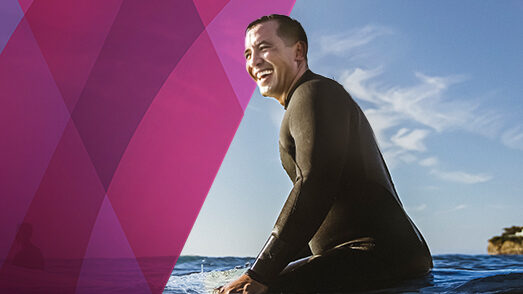 Man in a wetsuit sitting on a surfboard in ocean